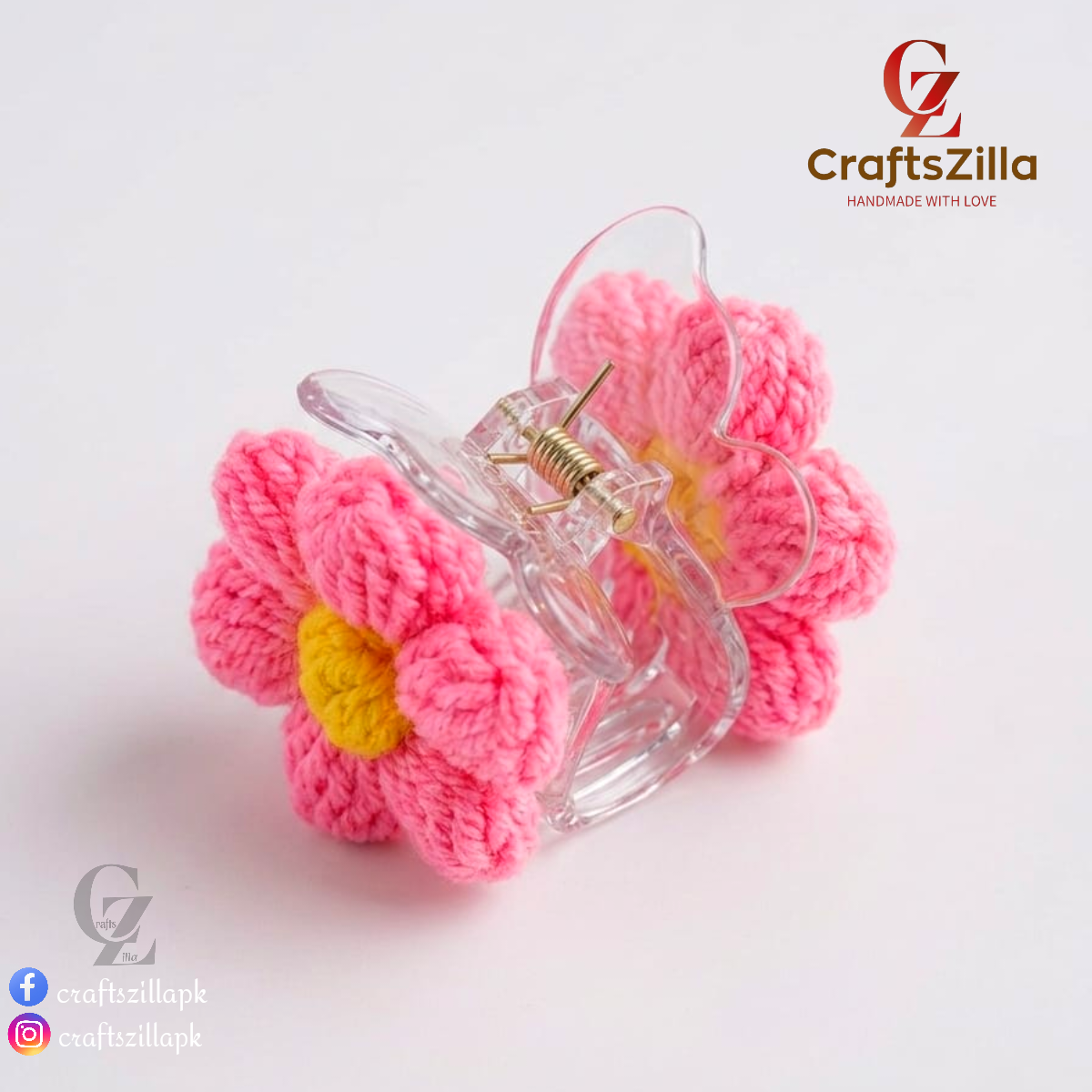 A pink crocheted flower hair claw clip with a yellow center and a clear plastic clip base, shown on a white background with CraftsZilla branding.