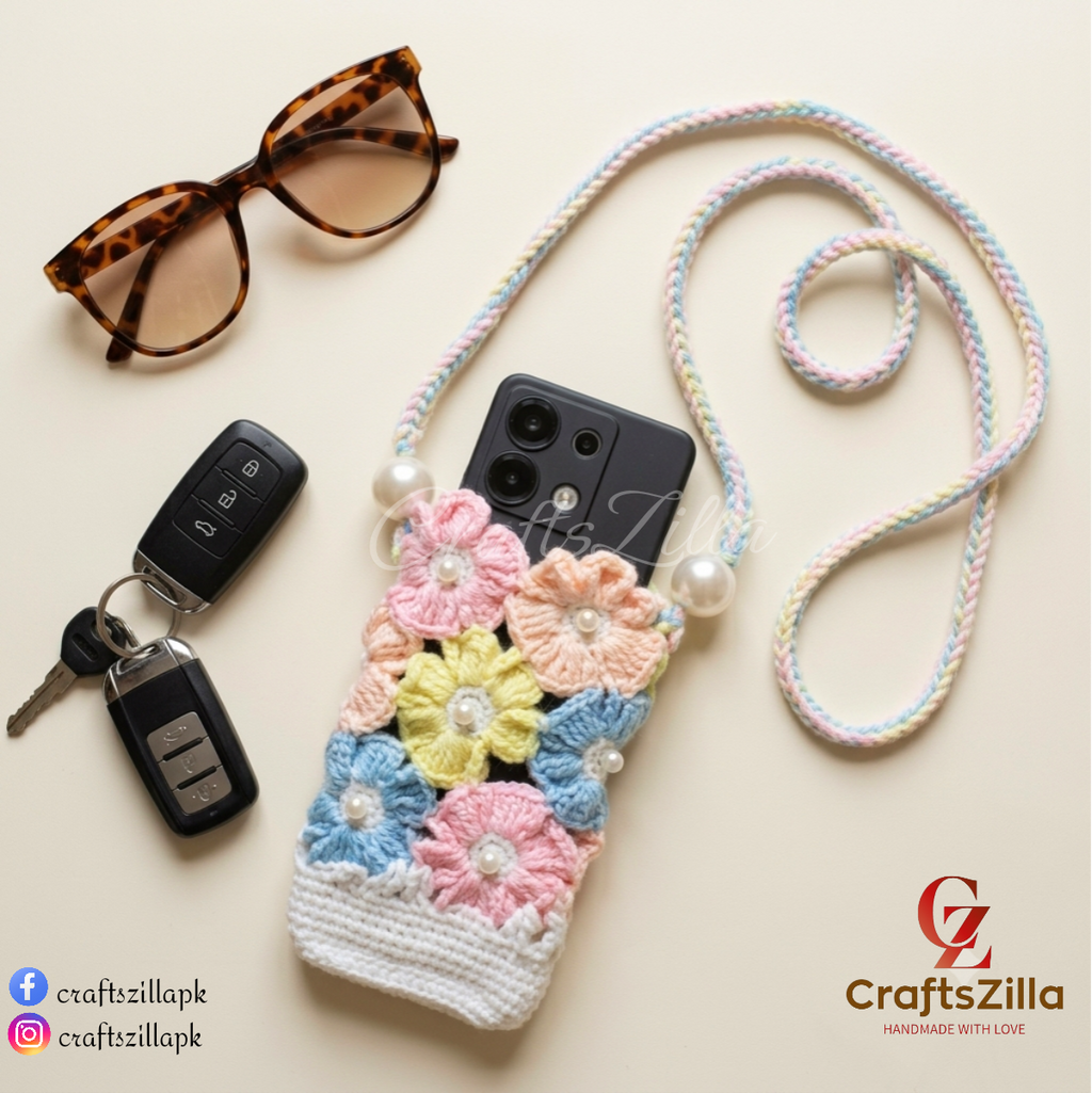 A handmade crocheted phone case with a floral design and a braided shoulder strap, styled on a light beige background with sunglasses, car keys, and a smartphone. The brand name 'CraftsZilla' is visible in the bottom right corner.