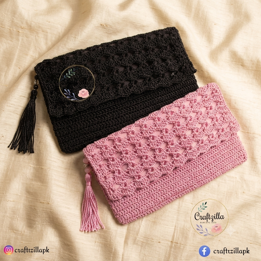 A product photograph displaying two handmade crocheted clutch purses arranged overlapping each other diagonally on a textured, light beige silk or satin fabric background. The top purse is matte black, and the bottom purse is light pink. Both clutches showcase a detailed, openwork crochet pattern on the front flap, a solid crochet texture on the main body, and a matching decorative tassel hanging from the left side. The image includes a circular "Craftzilla" floral logo overlay on the bottom right and soc