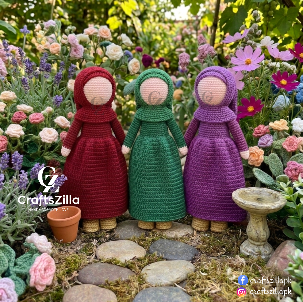 Three crocheted dolls wearing long dresses in red, green, and purple, standing on a stone path in a flower garden. A small pot and birdbath are nearby, with the CraftsZilla logo visible on the left.